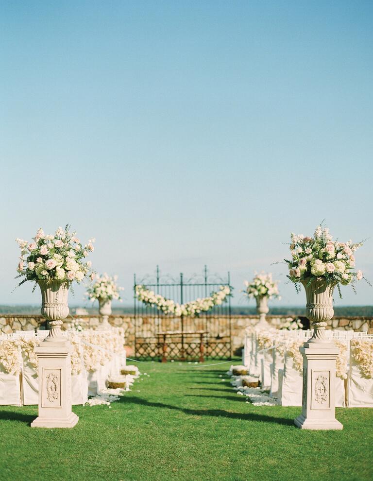 Rose flower arrangements and garlands at outdoor wedding ceremony