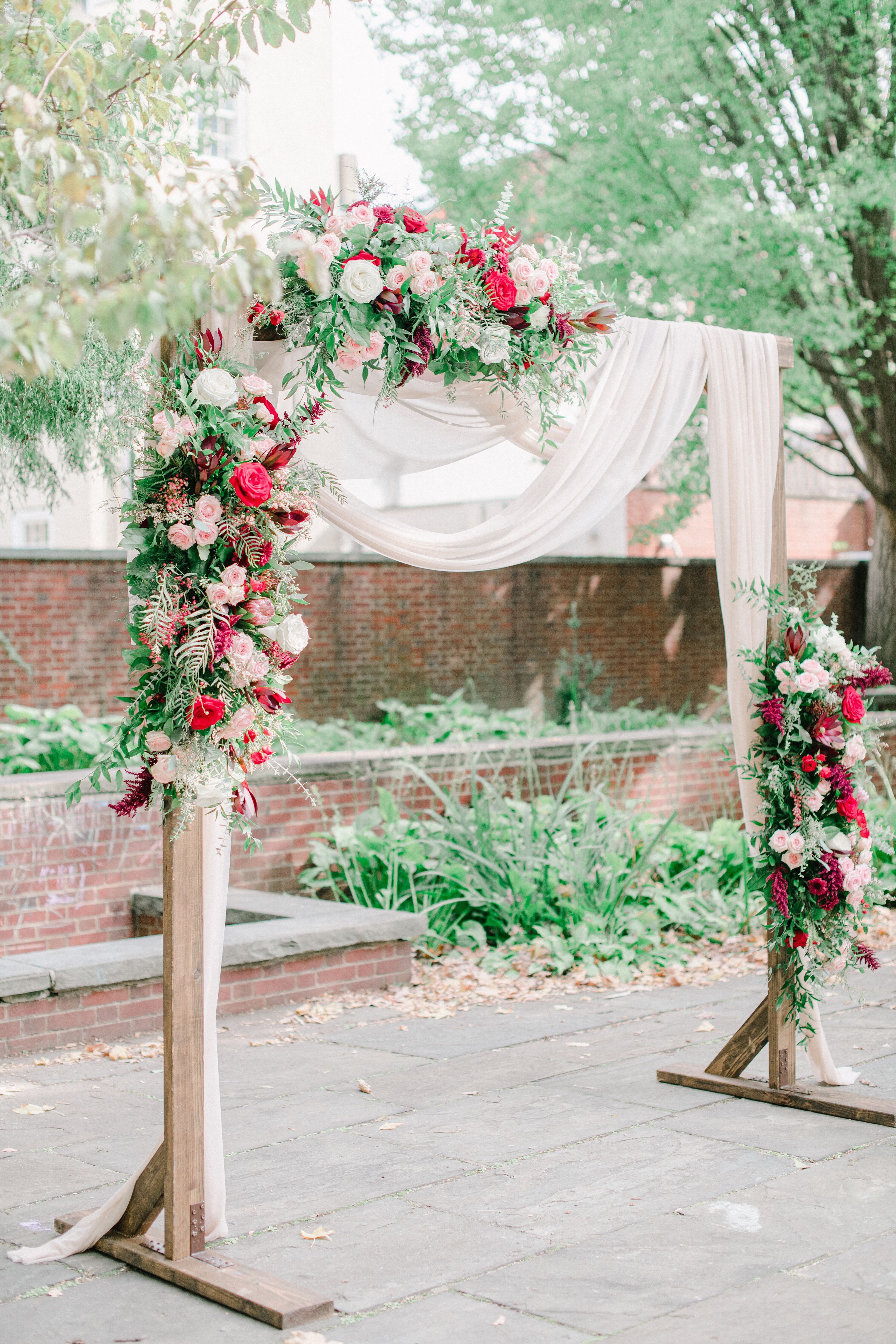 Wood Ceremony Arch With Draping and Bright Red Roses