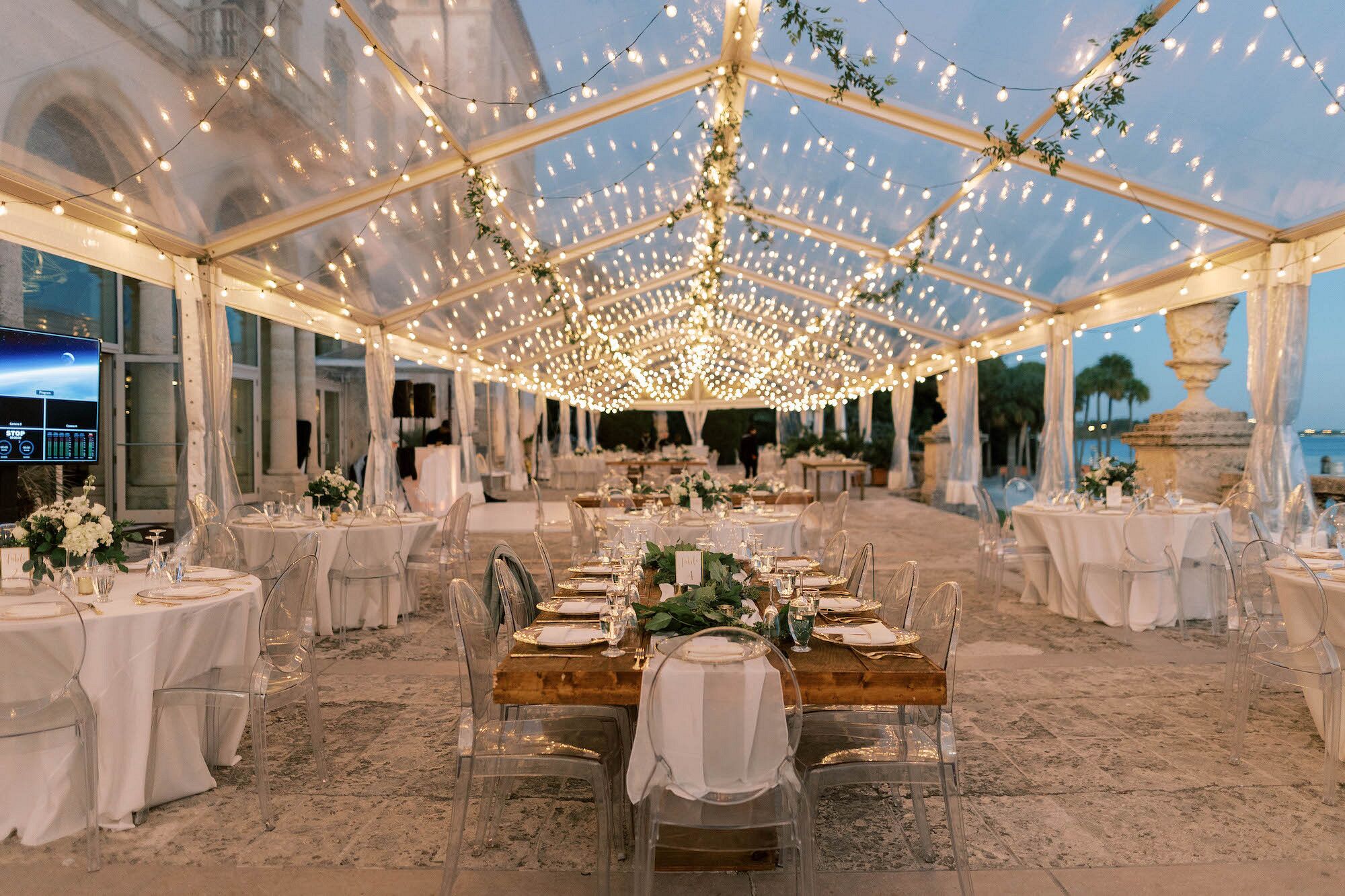 Clear-Tent Reception at Night Under String Lights, Simple Tables, Ghost ...