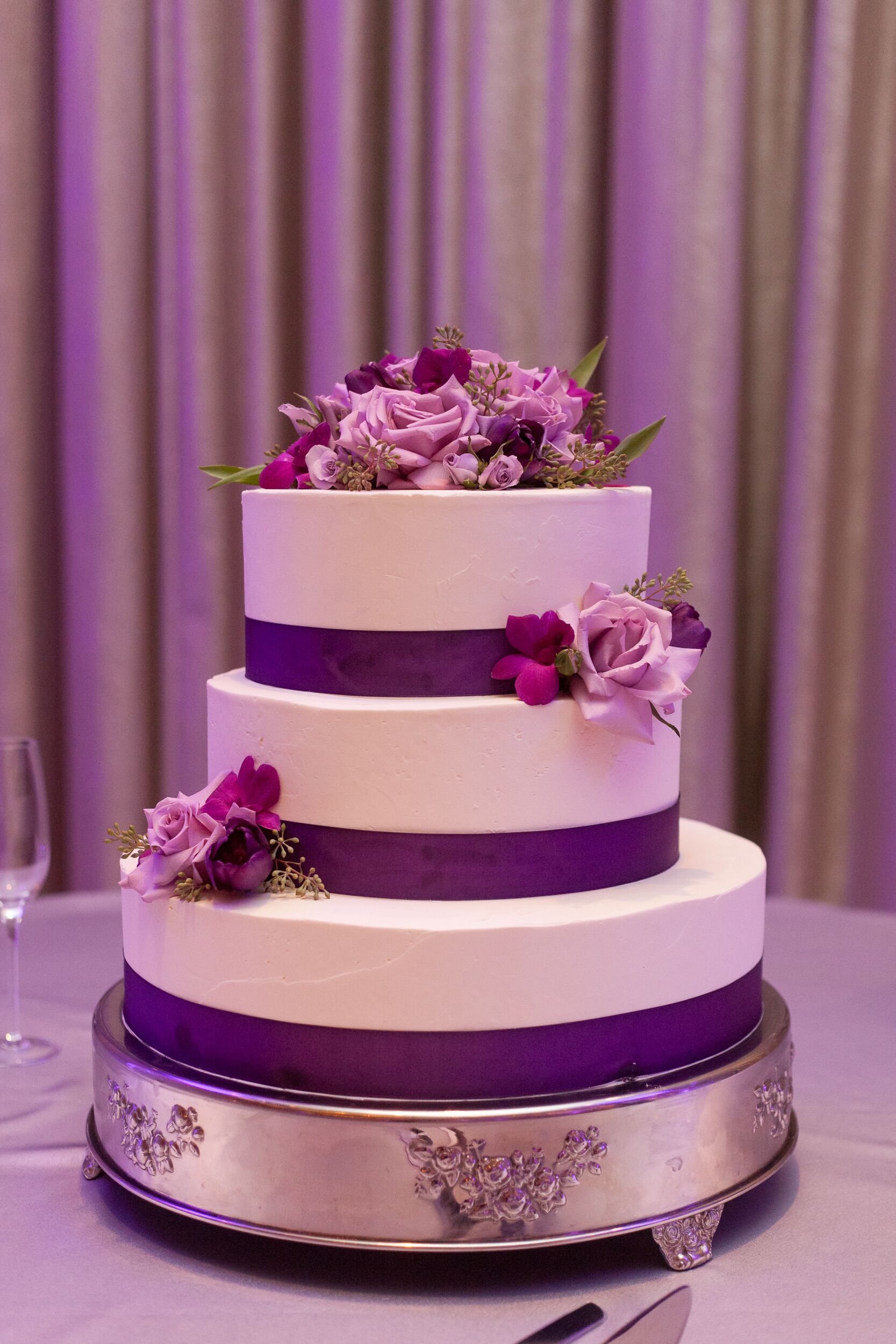 Wedding Cake with Purple Ribbon and Scattered Flowers