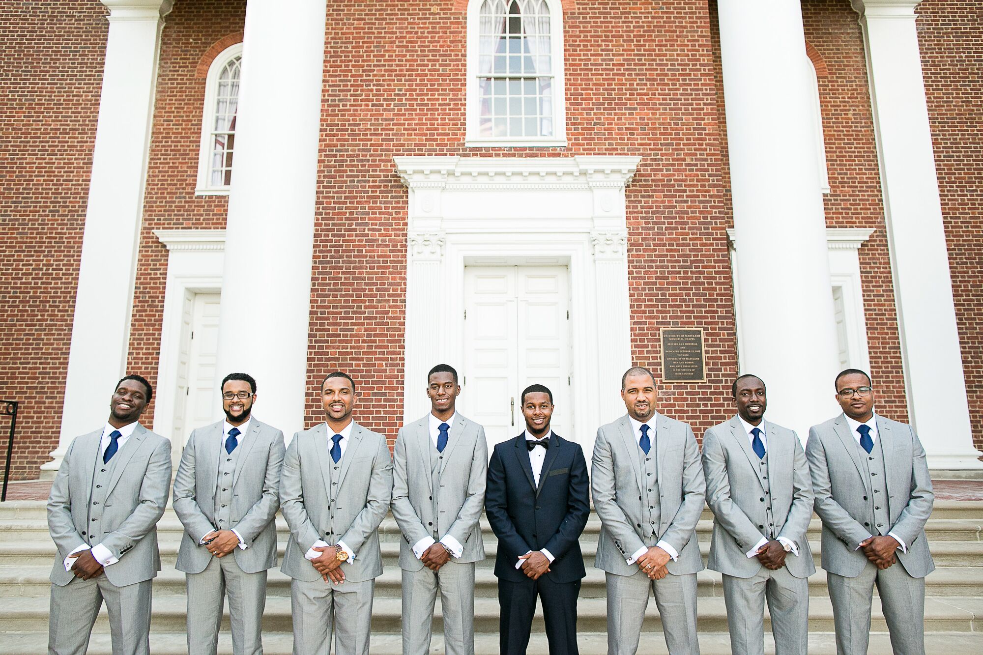 Groomsmen in Gray Suits and Navy Ties Groom in a Black Tuxedo