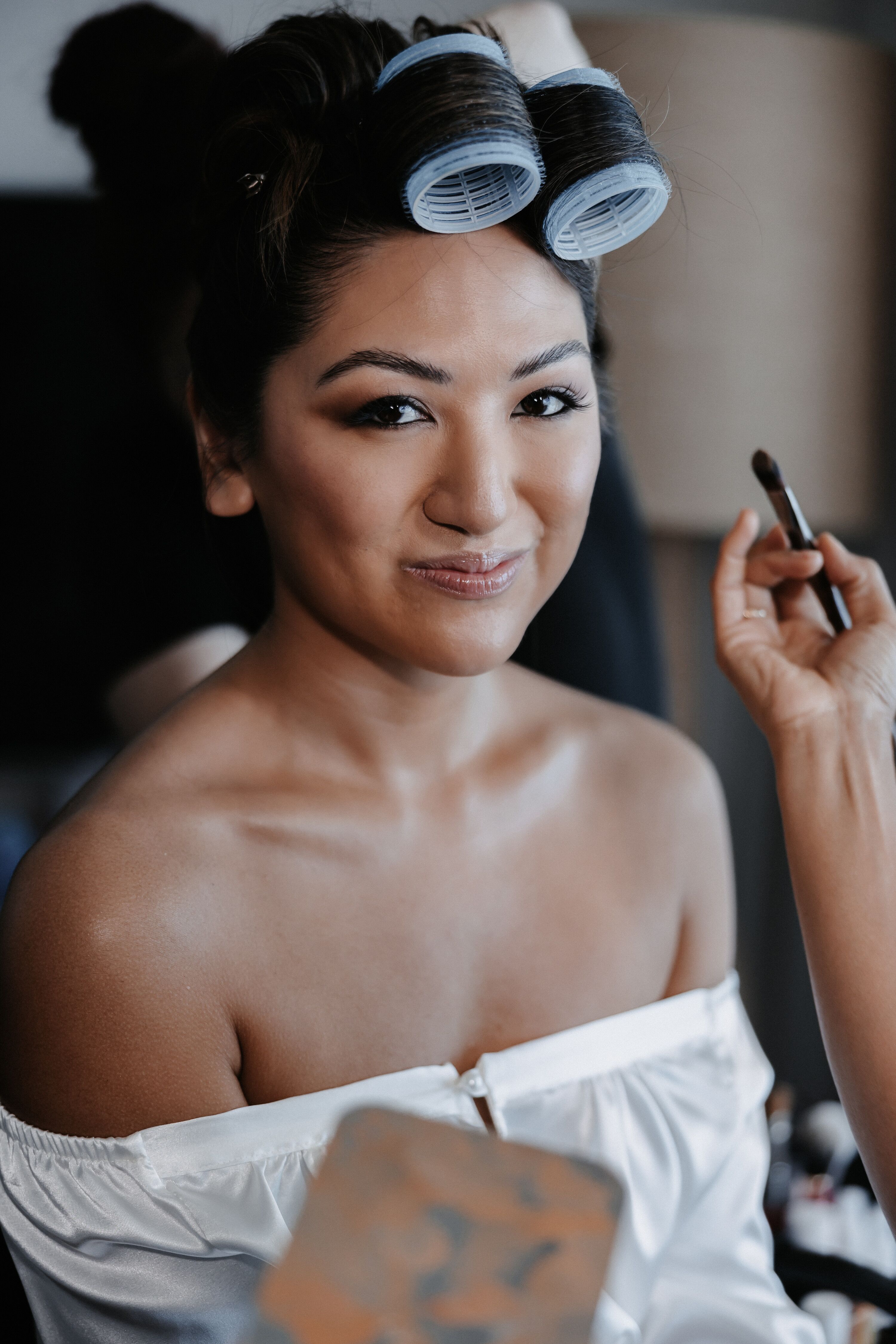 Bride In Curlers Getting Soft Dewy Makeup Look For Her Beach Wedding