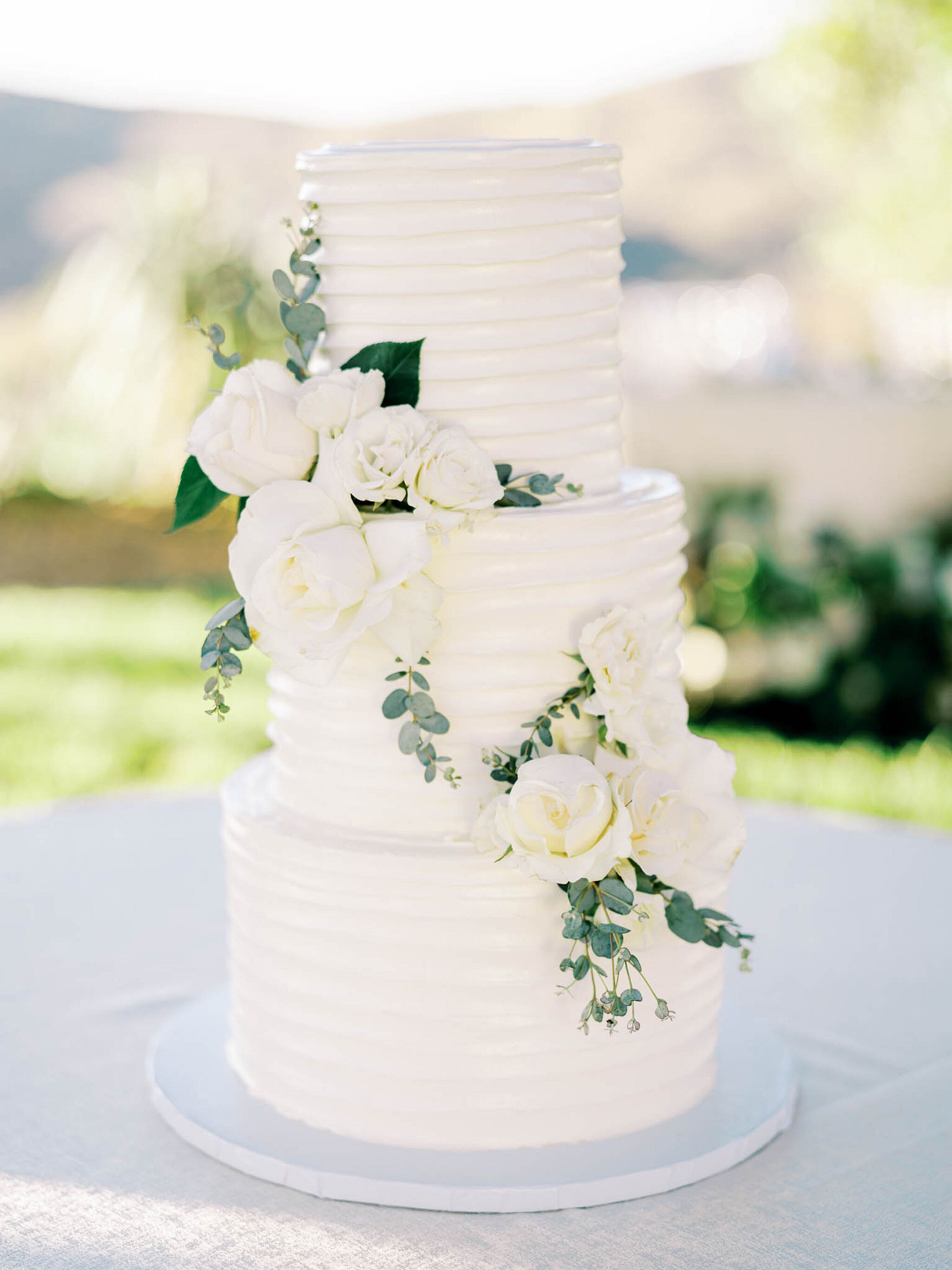 Three-Tier White Wedding Cake With Combed Buttercream and White Flowers