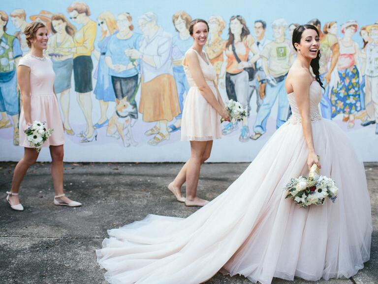 Bride walking with bridesmaids next to mural
