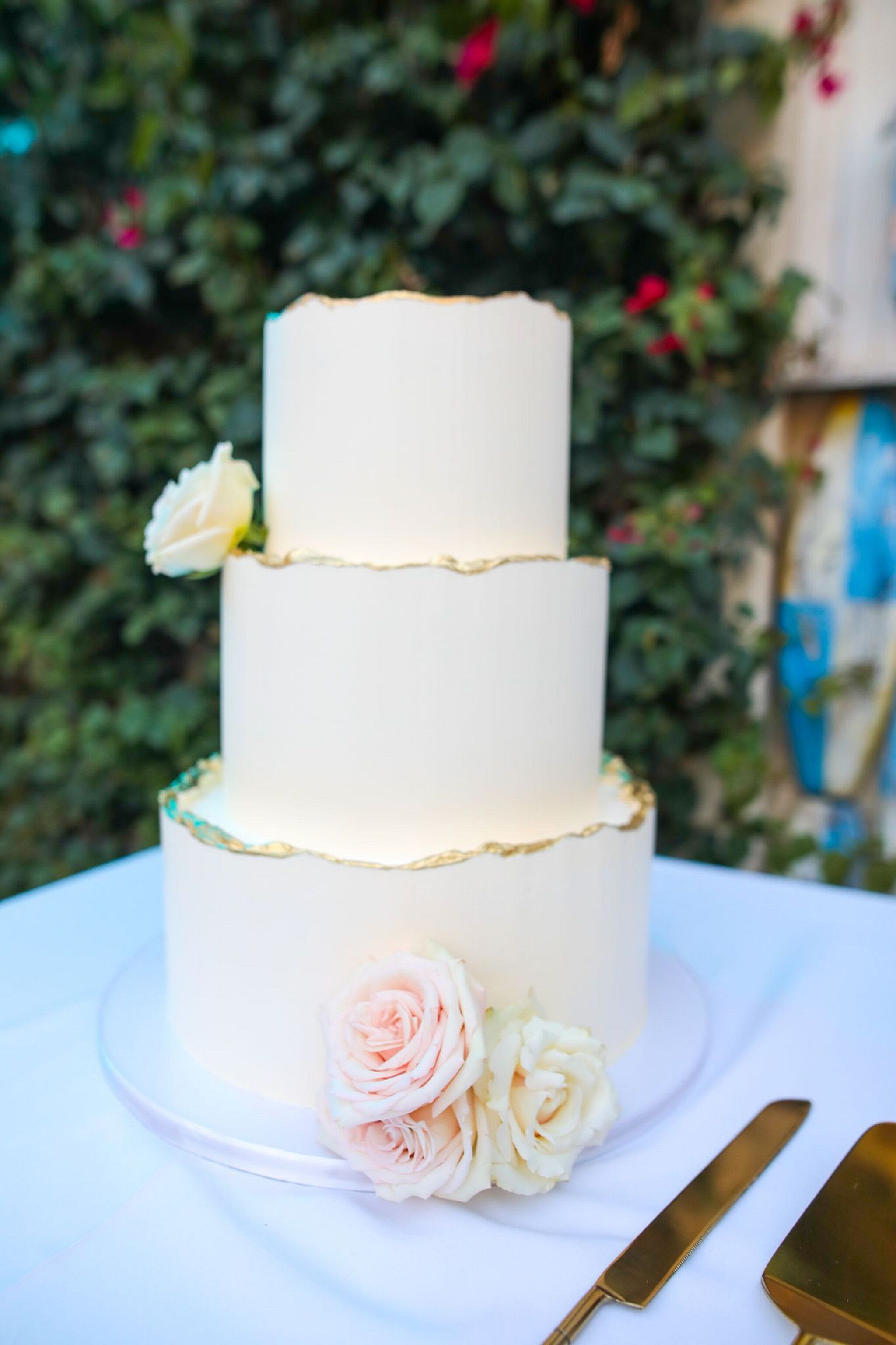 Three-Tier White Wedding Cake With Gold Hem and Real White-and-Blush Roses