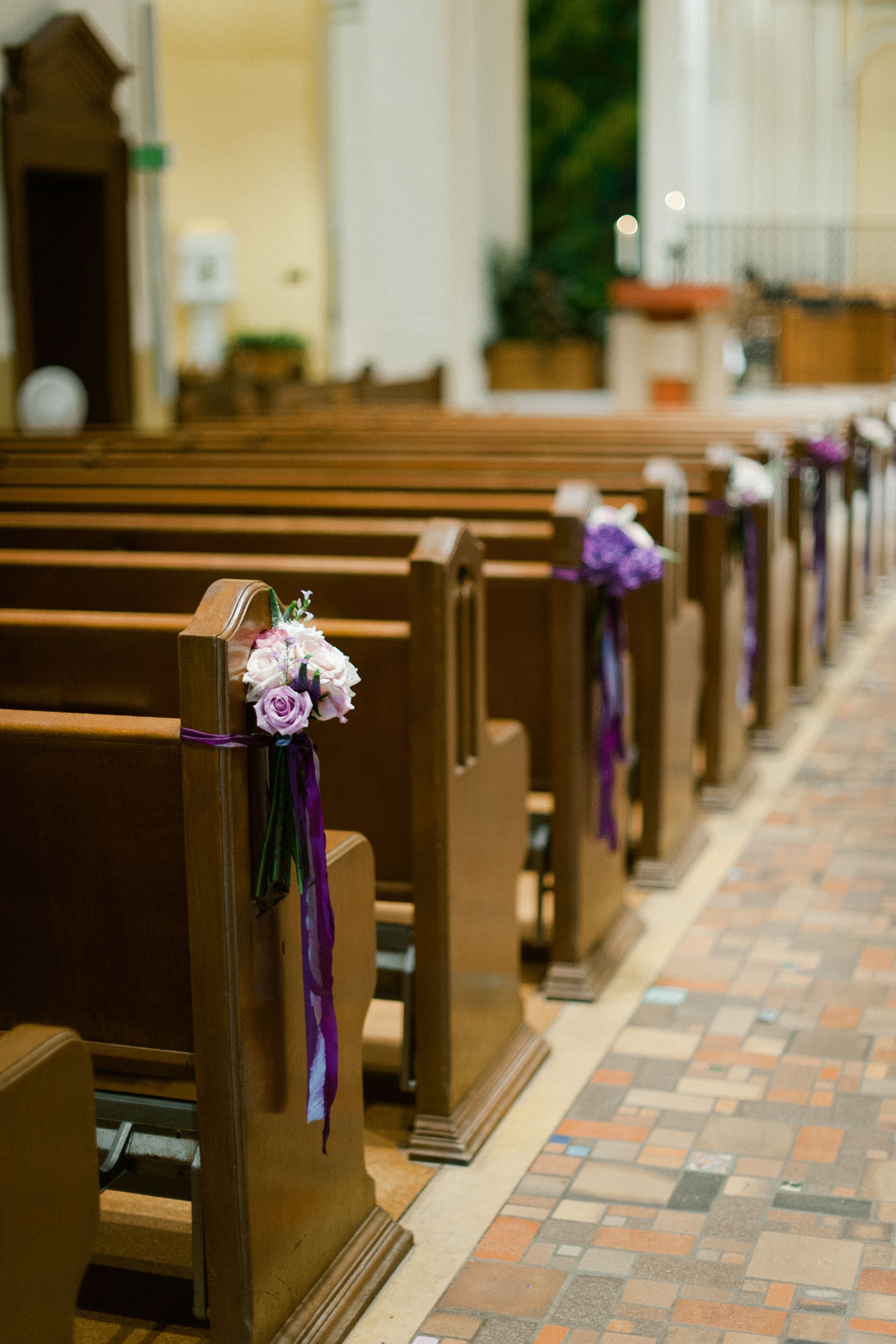 Church Pews Decorated with Flowers and Purple Ribbon