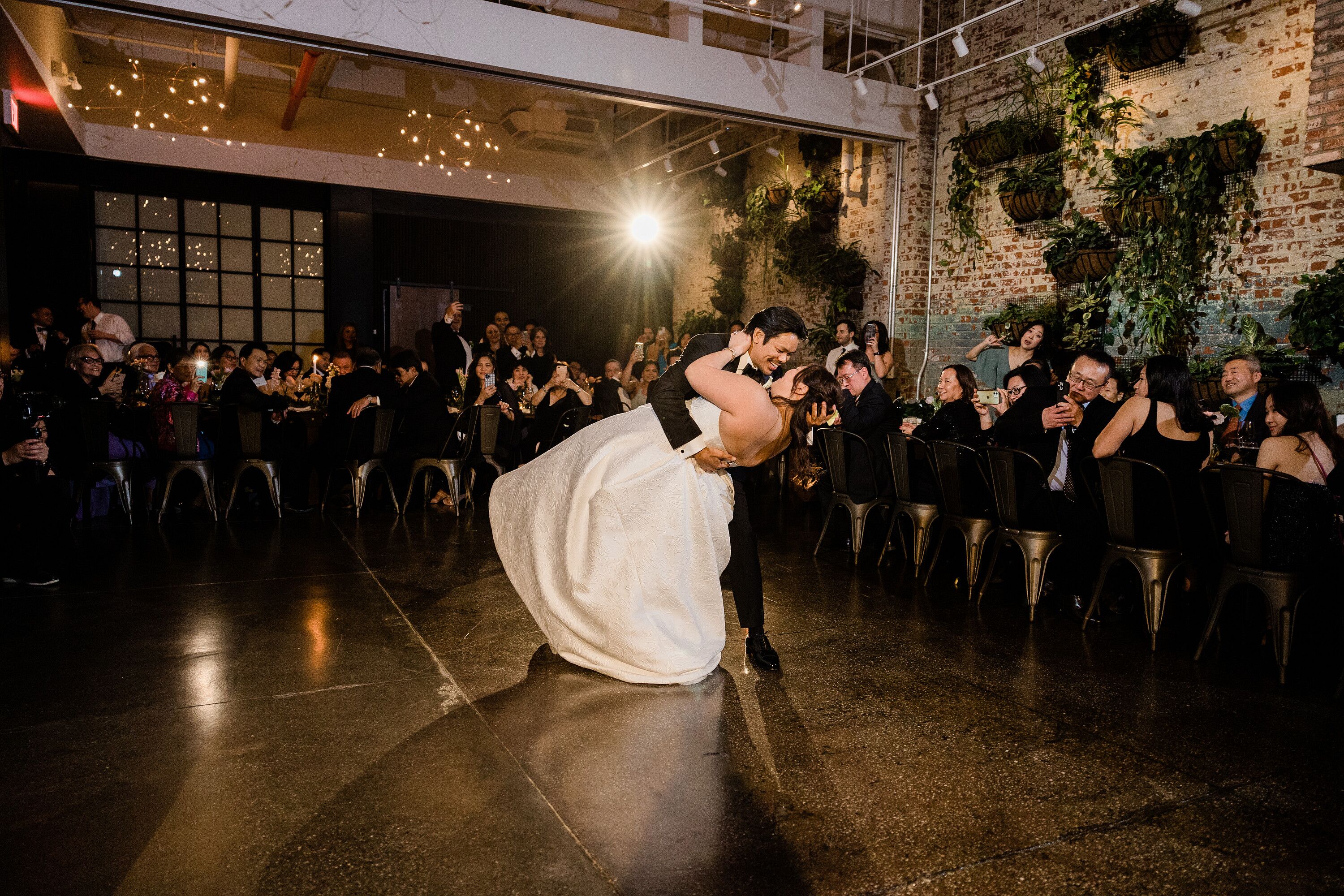 Bride and Groom Doing a Dip During First Dance in Warehouse in Winery