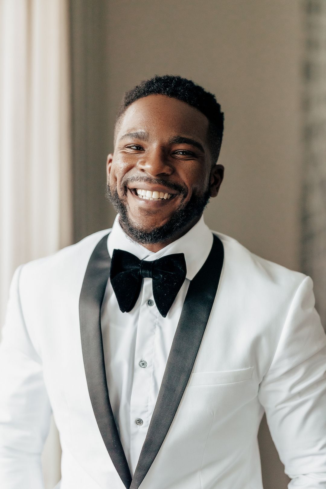 Groom In White Tuxedo Jacket With Black Trim And A Black Bow Tie