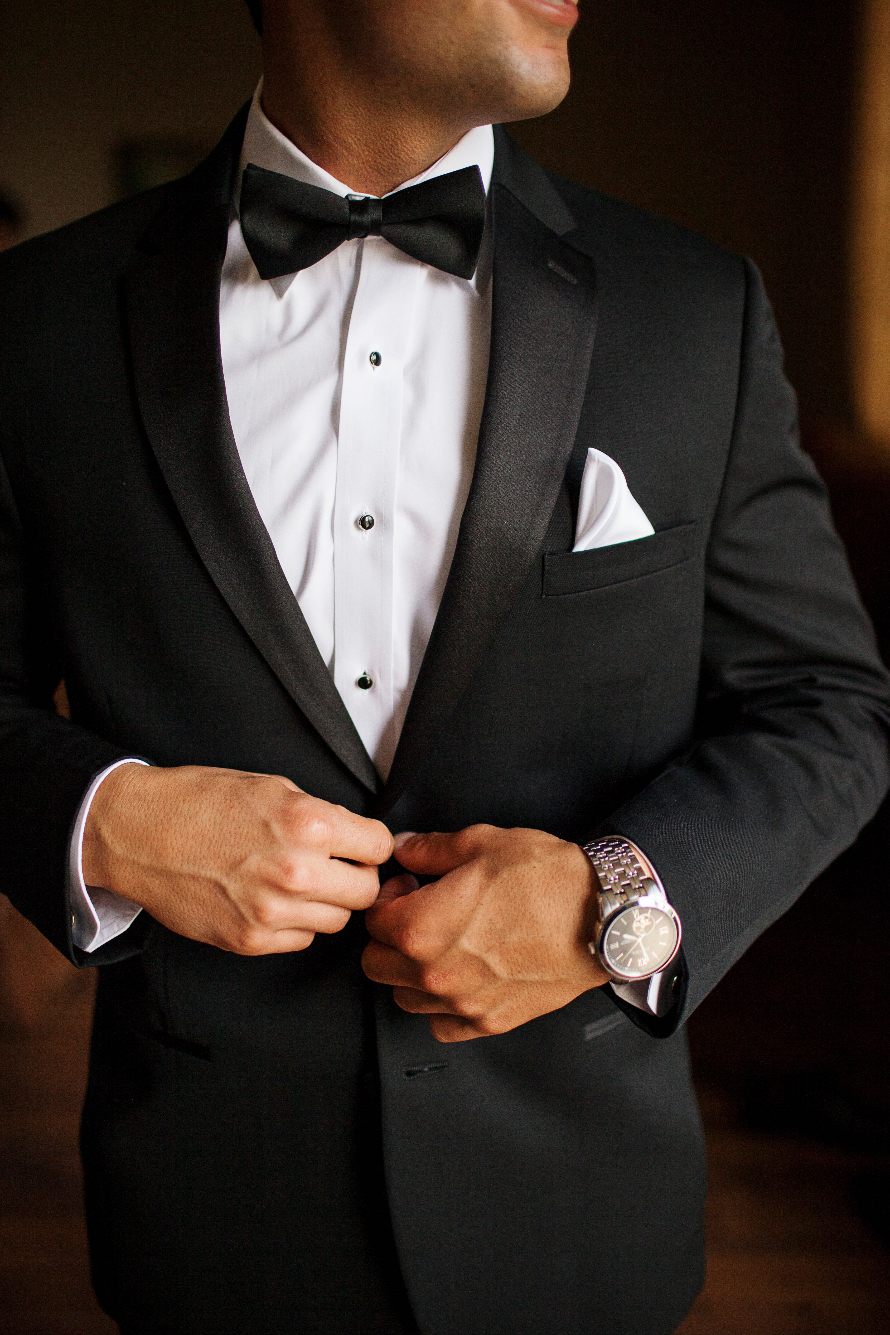 A man in a classic black suit with a black bow tie.