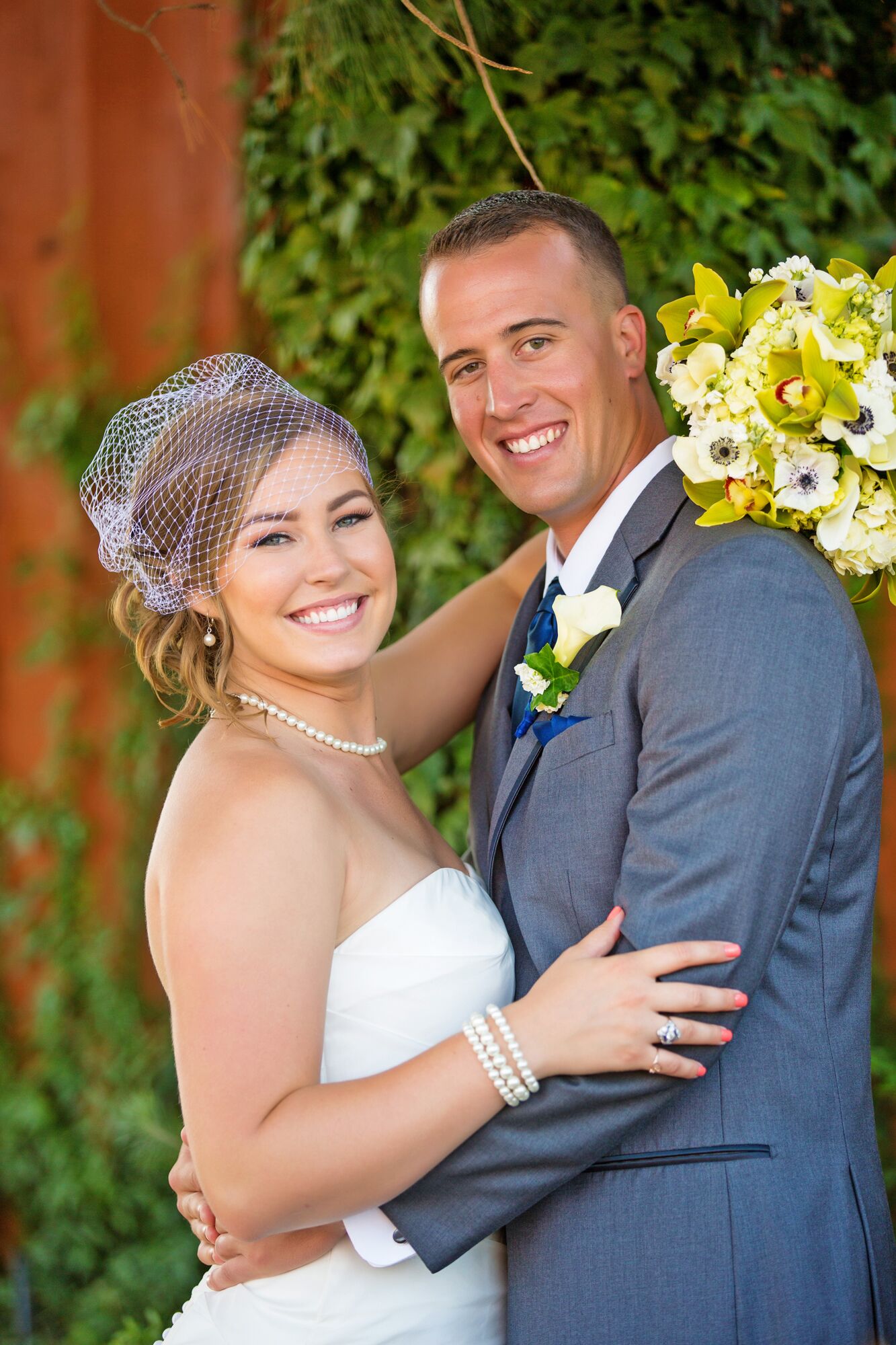 Bride and Groom Smile Surrounded by Greenery