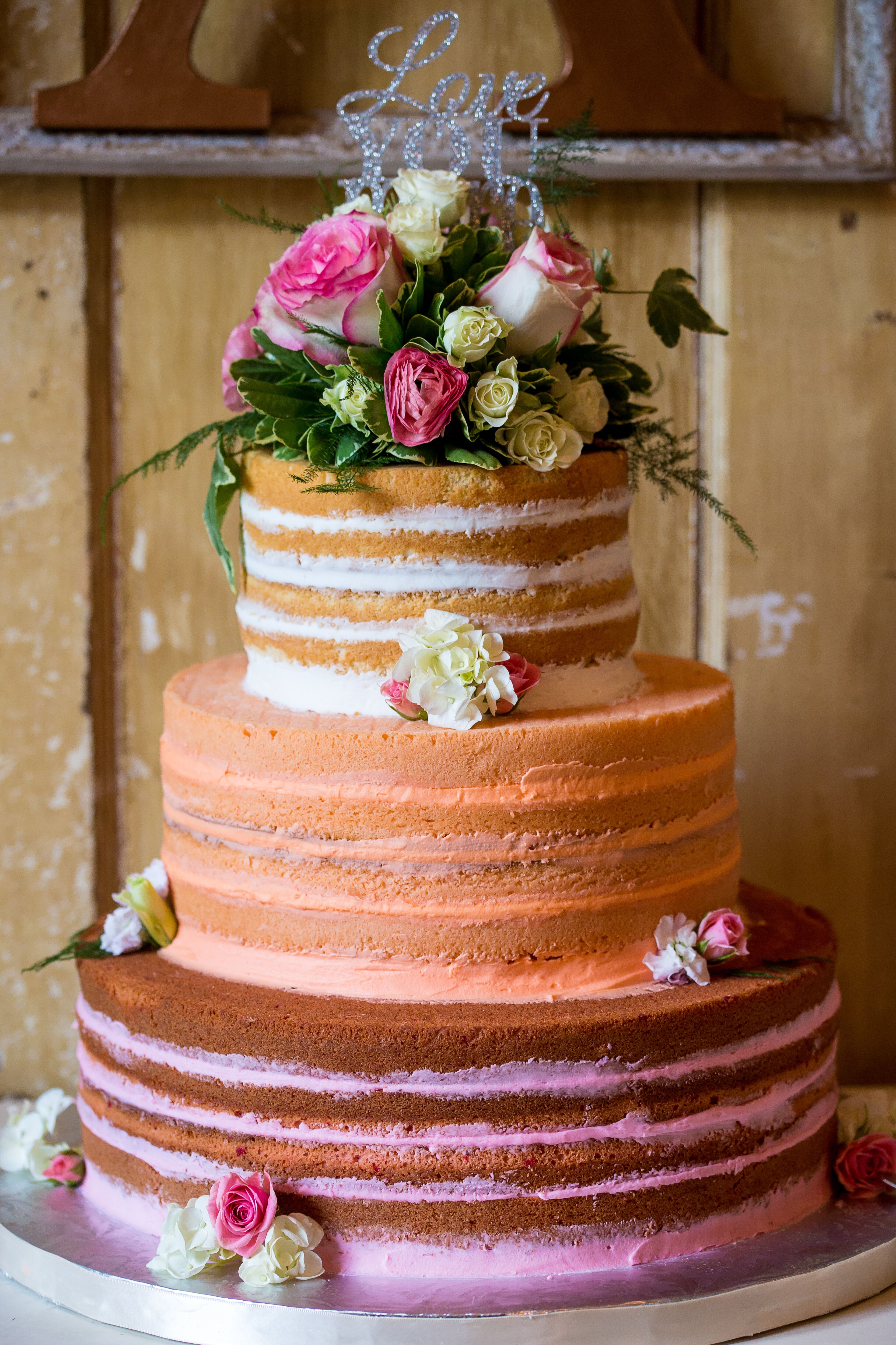 Three tier naked wedding cake decorated with burgundy 