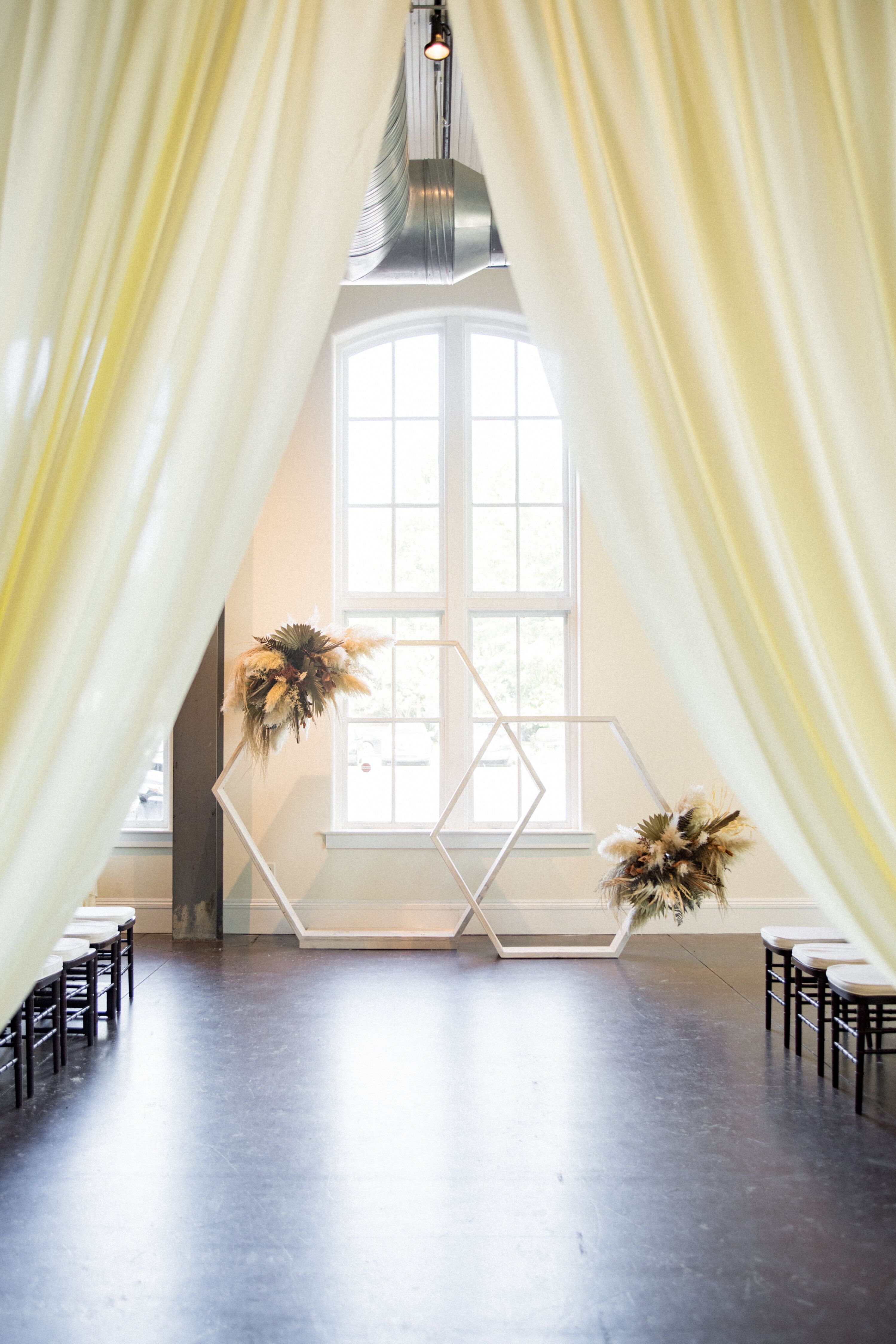 Indoor Ceremony Space With Geometric Arches and Neutral Florals, Grass