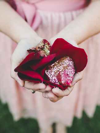 Bridesmaid holding glitter-covered red rose petals