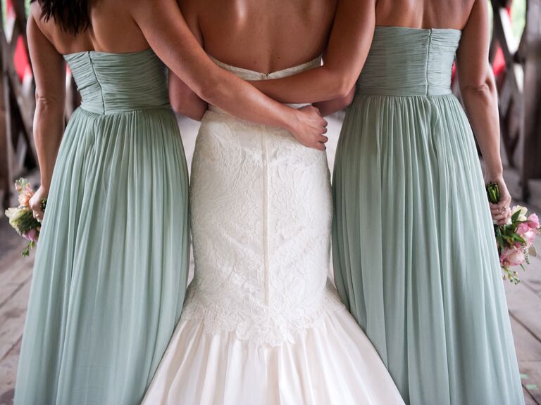 Two bridesmaids with their arms around the bride