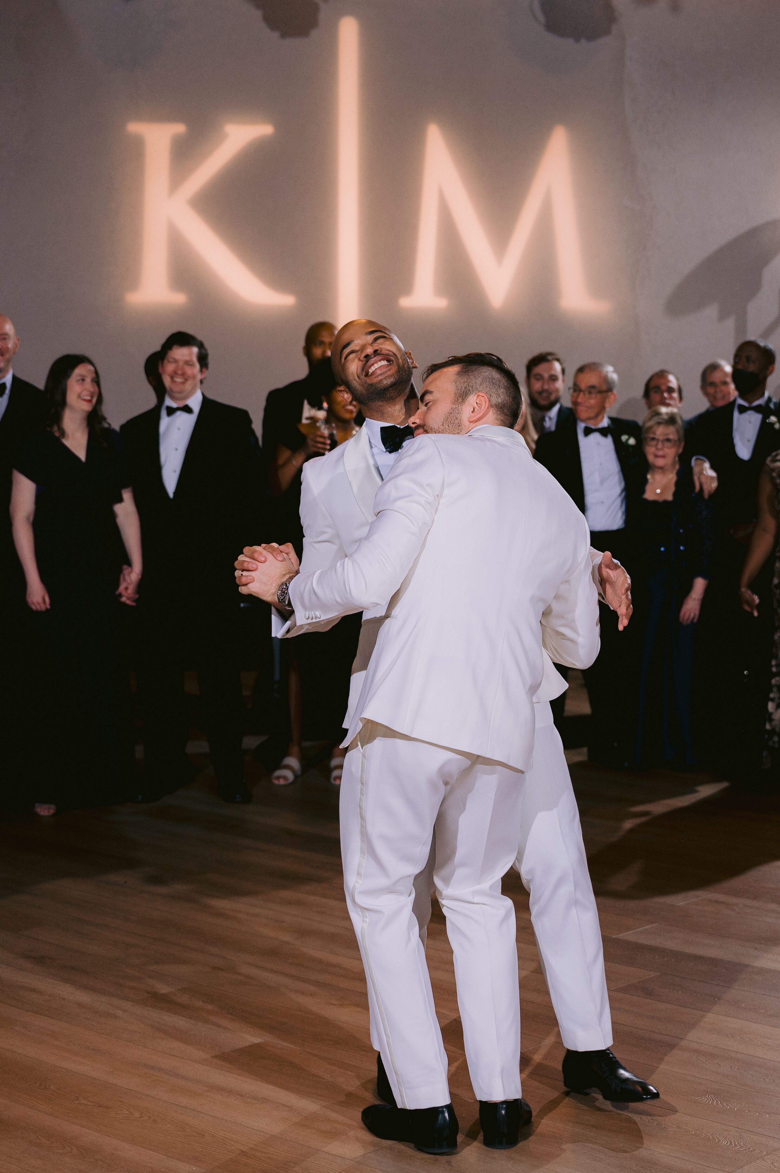 Grooms in White Tuxedos Doing First Dance Under Projection of Their ...