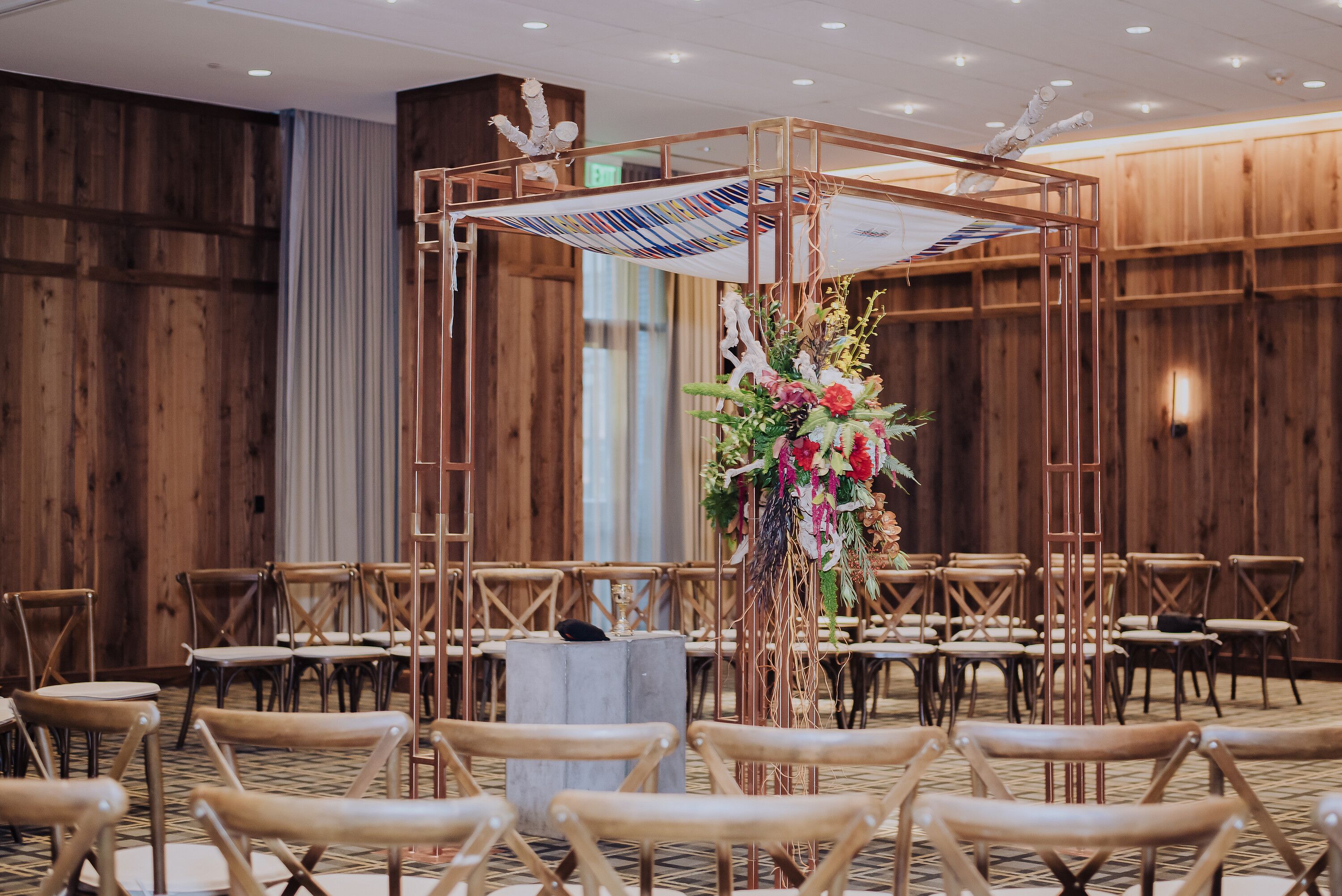 Modern Gold Chuppah With Flower Arrangements In Hotel Ballroom