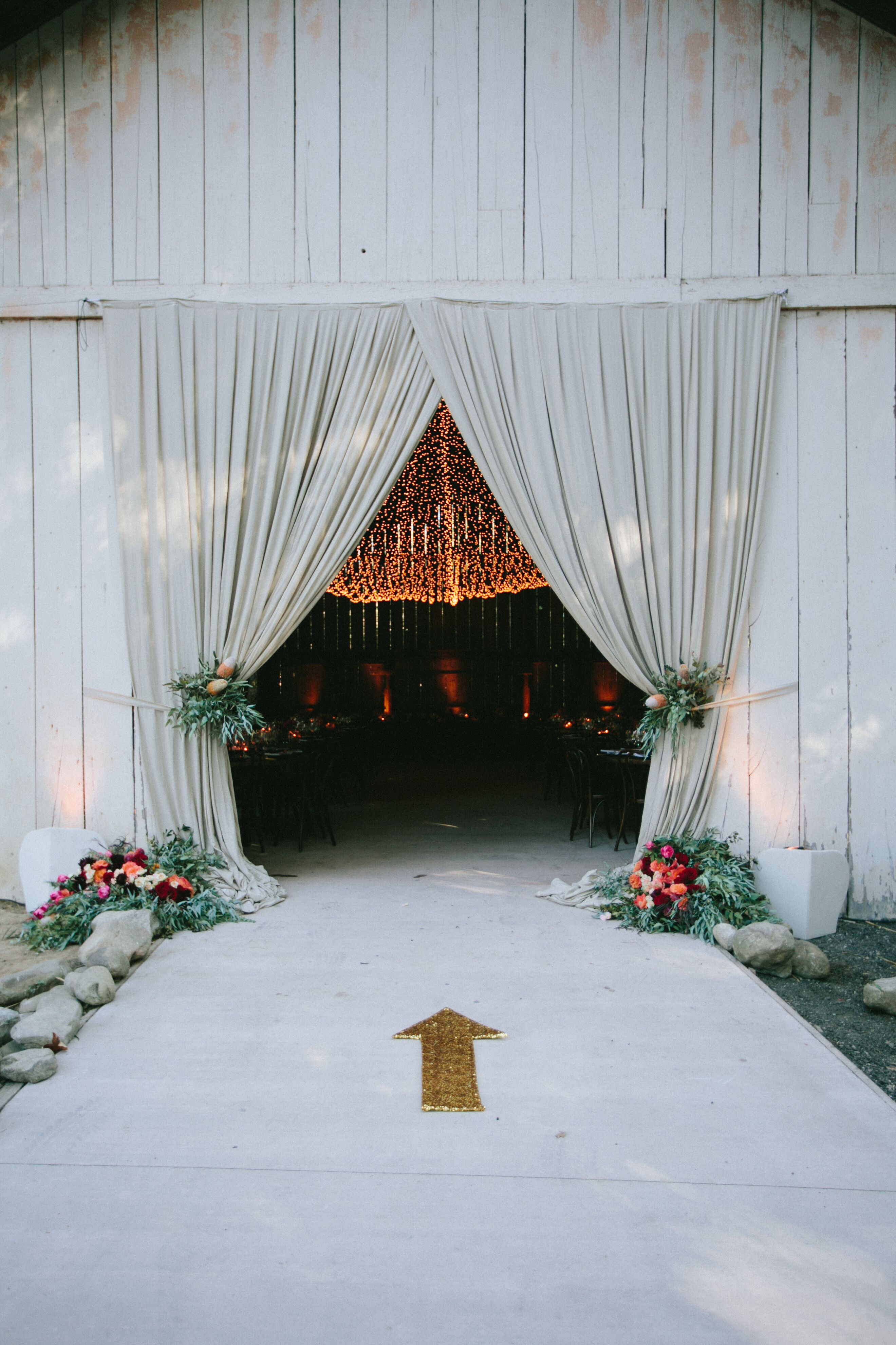 Fabric-Draped Barn Entrance with Bohemian Floral Arrangements